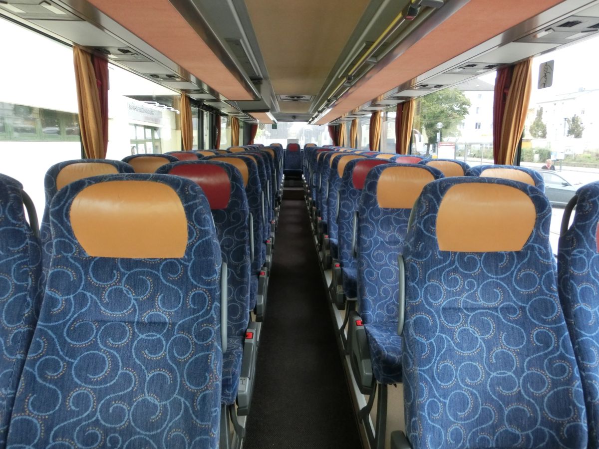 Innenraum des Setra S 315 UL-GT von Josef Kalb aus Norlaching bei Dorfen.
Verbaut sind hier 51 Fahrgastsitze plus 2 Reiseleiterplätze. Die Fahrgastsitze sind Schlafsessel vom Modell Setra 'Top', die über Kurbelarmlehnen, Gurte, Fußrasten und Lederkopfteile verfügen und auf den 330 mm hohen Podesten montiert sind. Auch der Mittelgang ist in diesem Fahrzeug erhöht, sodass sich der gesamte Innenboden auf dem Niveau der H/GT-Modelle befindet. Zur weiteren Innenausstattung gehören die Reisebus-Innenbeleuchtung, Deckensets mit Lüftungsdüsen und Leselampen, Vorhänge und eine TV-Anlage mit DVD-Laufwerk und zwei Monitoren.