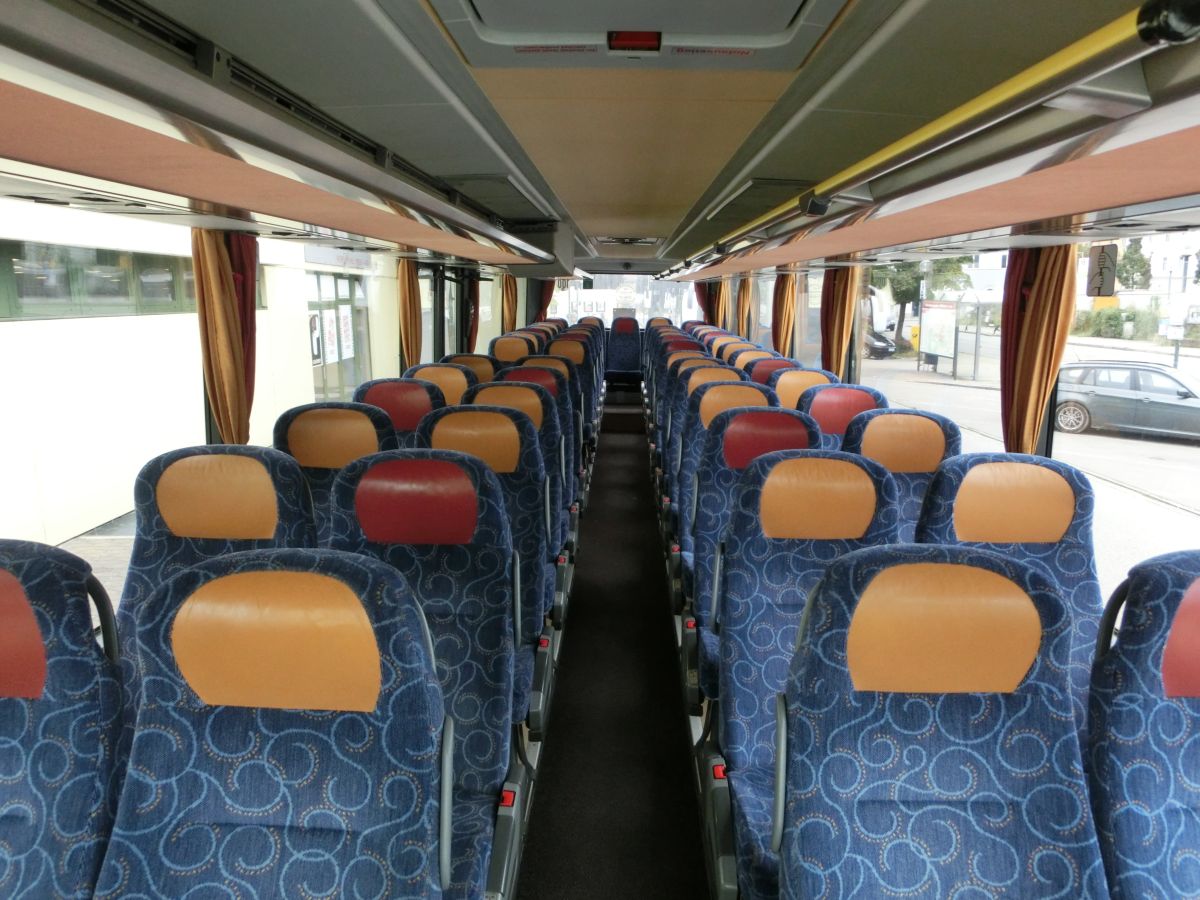 Innenraum des Setra S 315 UL-GT von Josef Kalb aus Norlaching bei Dorfen.
Verbaut sind hier 51 Fahrgastsitze plus 2 Reiseleiterplätze. Die Fahrgastsitze sind Schlafsessel vom Modell Setra 'Top', die über Kurbelarmlehnen, Gurte, Fußrasten und Lederkopfteile verfügen und auf den 330 mm hohen Podesten montiert sind. Auch der Mittelgang ist in diesem Fahrzeug erhöht, sodass sich der gesamte Innenboden auf dem Niveau der H/GT-Modelle befindet. Zur weiteren Innenausstattung gehören die Reisebus-Innenbeleuchtung, Deckensets mit Lüftungsdüsen und Leselampen, Vorhänge und eine TV-Anlage mit DVD-Laufwerk und zwei Monitoren.