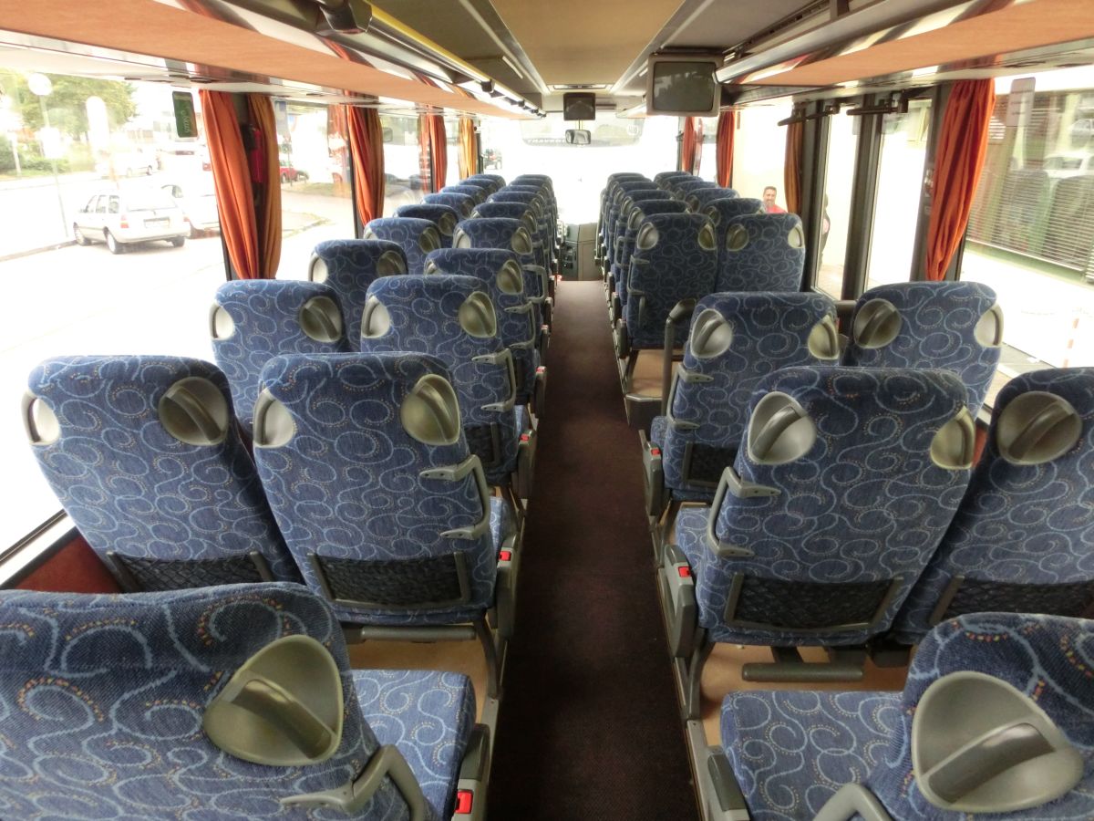 Innenraum des Setra S 315 UL-GT von Josef Kalb aus Norlaching bei Dorfen.
Verbaut sind hier 51 Fahrgastsitze plus 2 Reiseleiterplätze. Die Fahrgastsitze sind Schlafsessel vom Modell Setra 'Top', die über Kurbelarmlehnen, Gurte, Fußrasten und Lederkopfteile verfügen und auf den 330 mm hohen Podesten montiert sind. Auch der Mittelgang ist in diesem Fahrzeug erhöht, sodass sich der gesamte Innenboden auf dem Niveau der H/GT-Modelle befindet. Zur weiteren Innenausstattung gehören die Reisebus-Innenbeleuchtung, Deckensets mit Lüftungsdüsen und Leselampen, Vorhänge und eine TV-Anlage mit DVD-Laufwerk und zwei Monitoren.